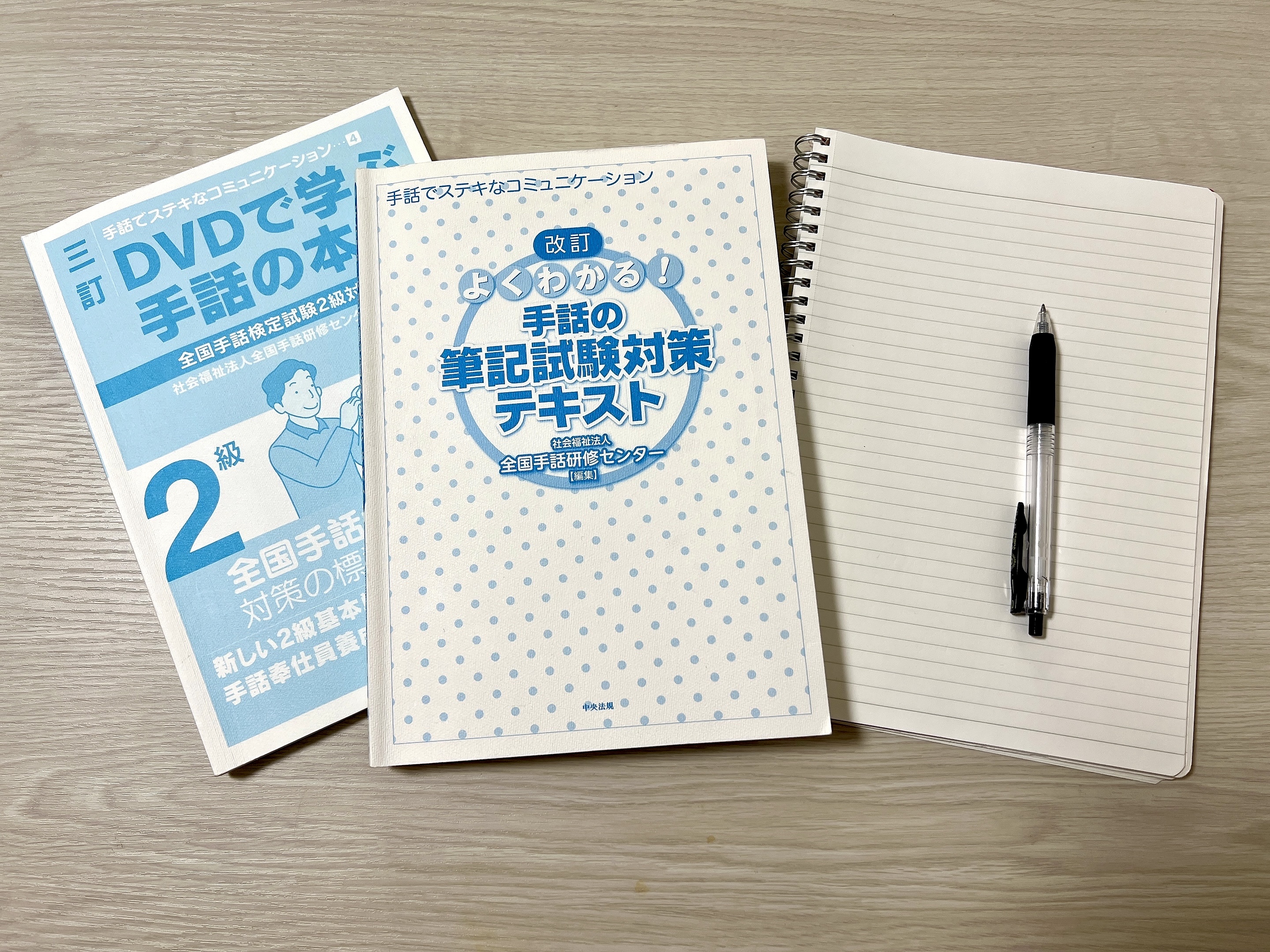 全国手話検定2級の教材と筆記試験対策テキスト、ノートとペン