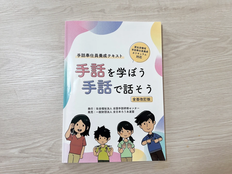 机に置いた手話奉仕員養成テキスト『手話を学ぼう 手話で話そう』全面改訂版の表紙