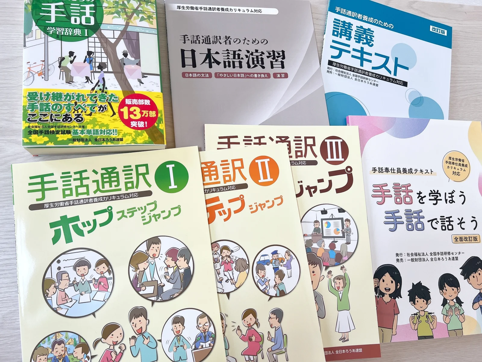 手話通訳Ⅰ・Ⅱ・Ⅲ、日本語演習、講義テキスト、手話辞典などを机に並べた写真