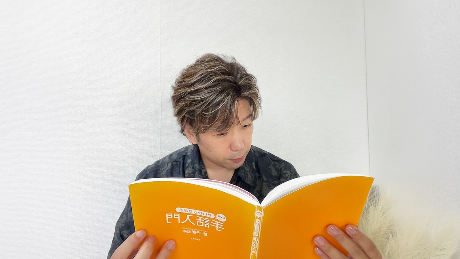 筆者が『ゼロからわかる手話入門』を開いて勉強している様子
