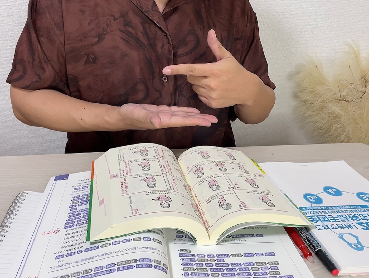筆者が『わたしたちの手話 学習辞典Ⅰ』を開いて手話を練習している様子