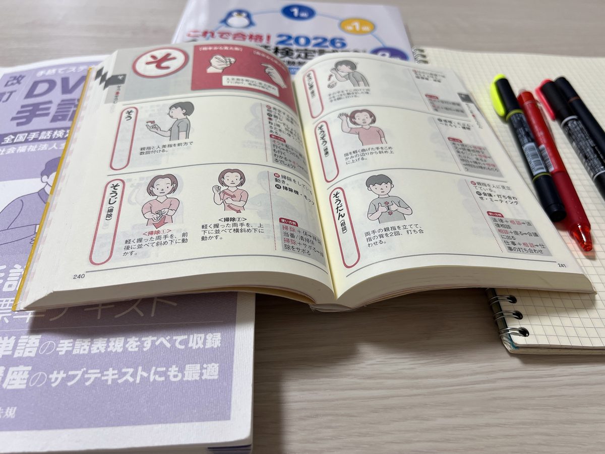 教材やノートのそばで、机の上に開いて置いた実用手話辞典