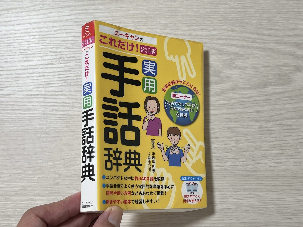 手で持った実用手話辞典の背表紙と厚み